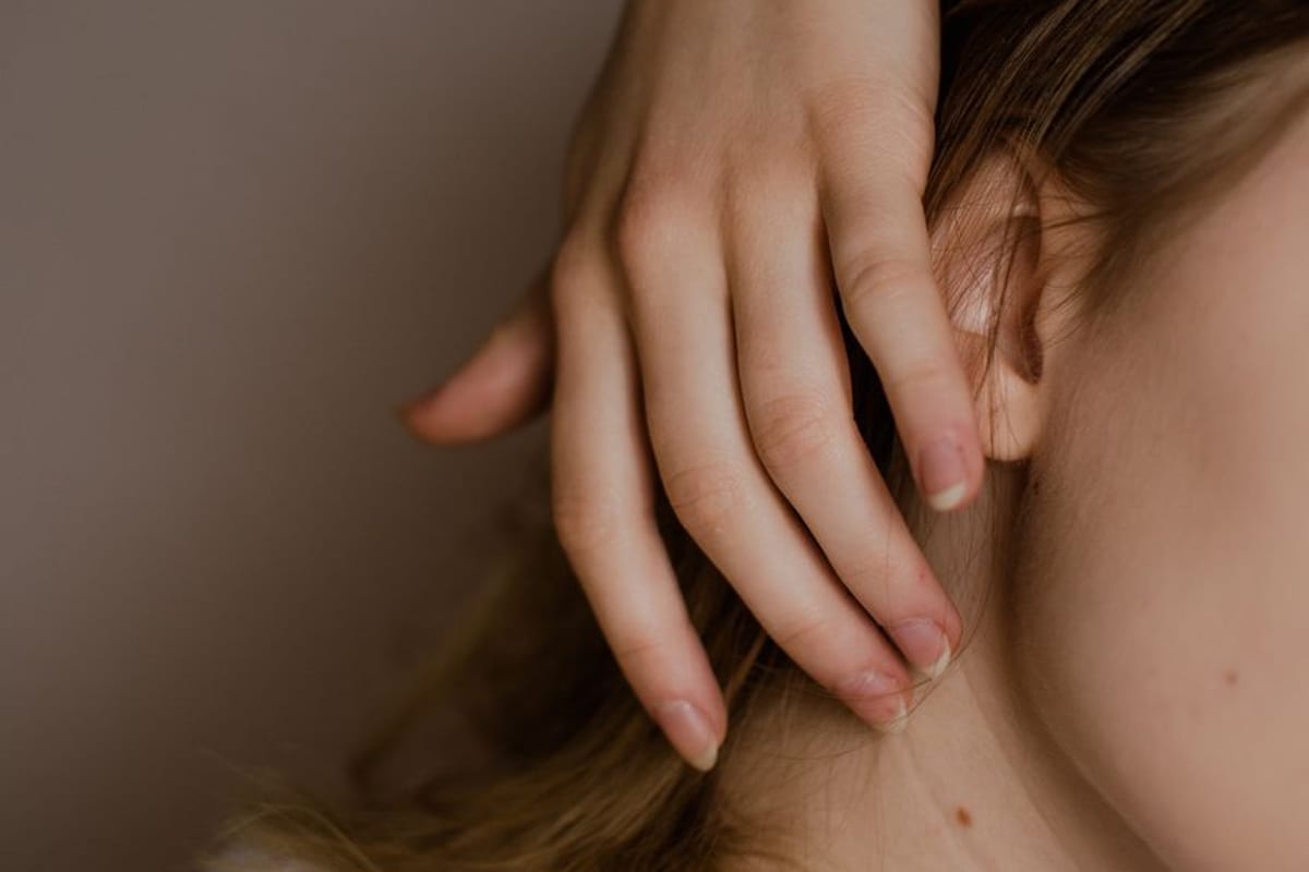 A hand resting along the jaw and neck, face cropped out of frame