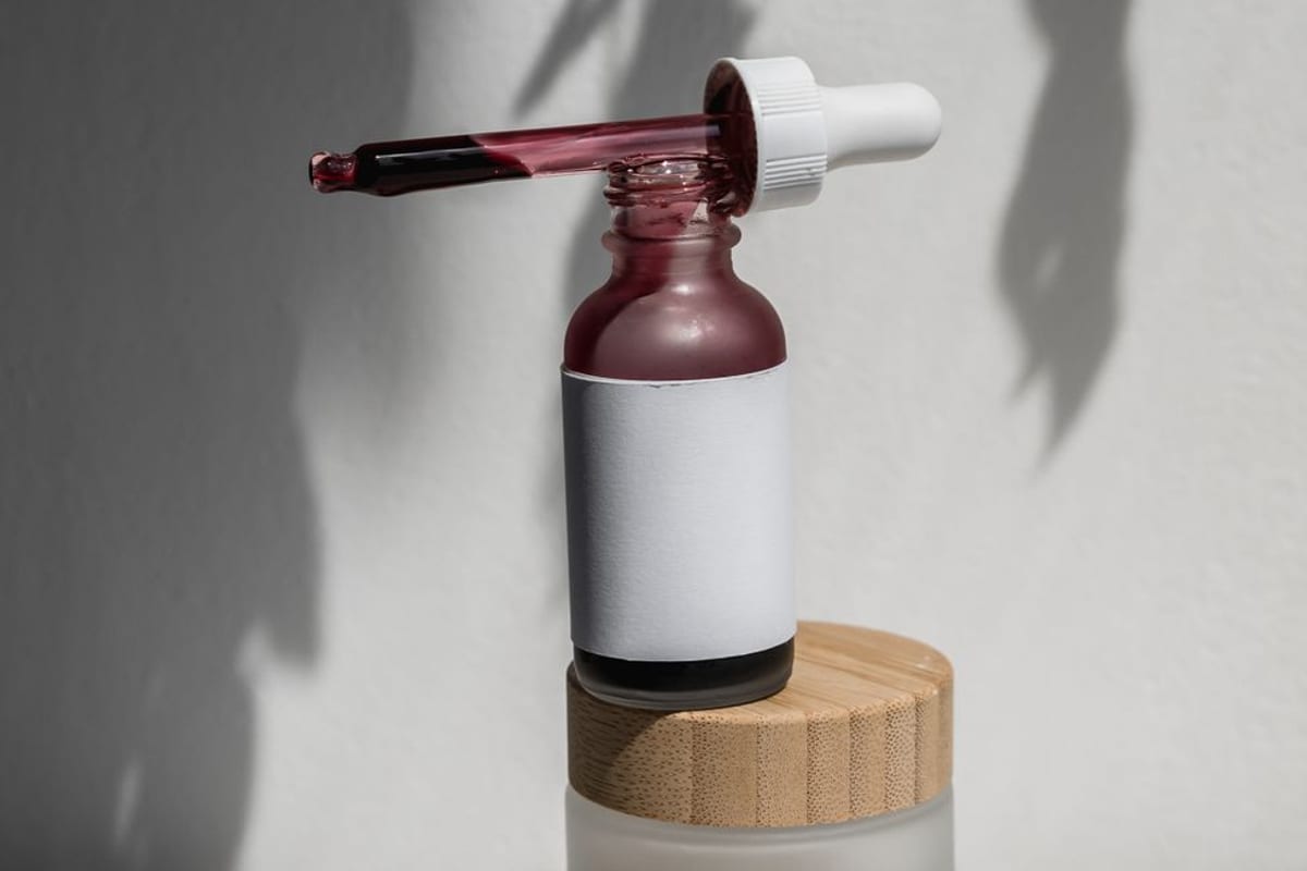 A serum bottle and dropper on a wooden lid, lit to cast long shadows